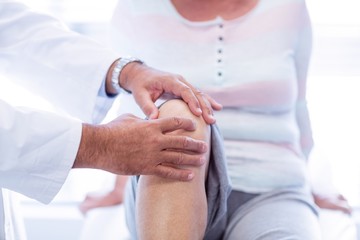 Obraz na płótnie Canvas Physiotherapist giving knee therapy to senior woman