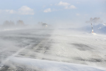 Fototapeta premium Intercity bus tries getting to a city by the highway during severe winter blizzard
