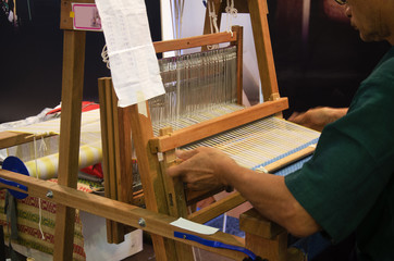 Fototapeta na wymiar Thai people using small loom or weaving machine for weaving show