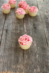 Pink cupcakes dotted with little hearts on old wood board