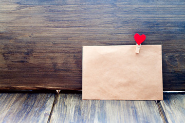The envelope of the Kraft paper clip in the shape of a heart on a wooden background, Valentine's...