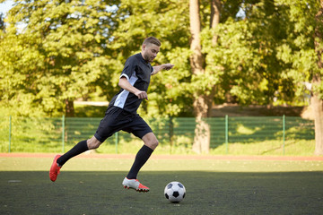 soccer player playing with ball on football field © Syda Productions
