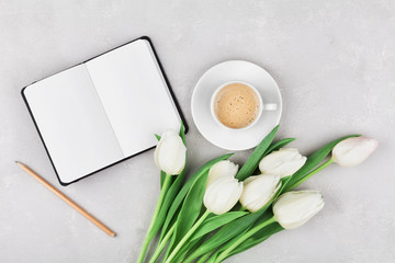 Woman working desk with coffee mug, notebook and spring tulip flowers top view in flat lay style.