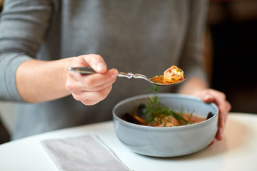 woman eating fish soup at cafe or restaurant