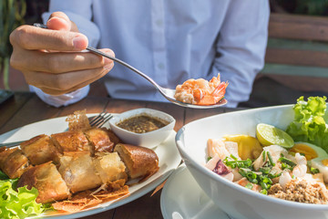 woman use spoon scoop shrimps from spicy seafood salad in restaurant.