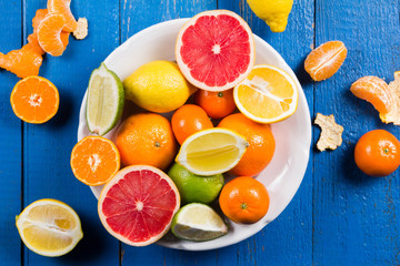 various types of citrus fruit on a blue painted wooden background