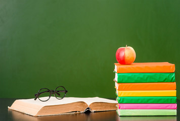 Books near empty green chalkboard. Sample for text