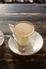 A cup of cappuccino on the table in a cafe on a sunny day