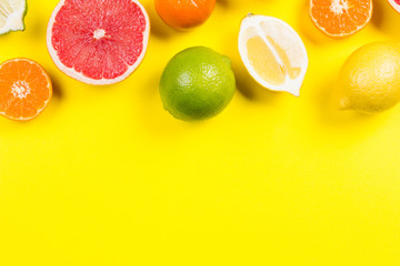 Several kinds of whole and cut citrus on a yellow background
