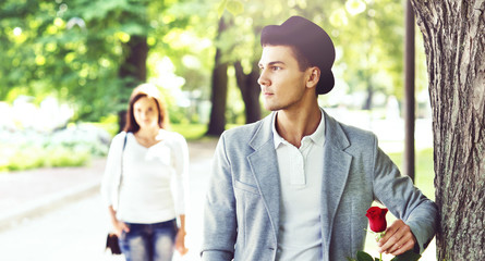 Young handsome man waiting for his girlfriend in the park. Love, relationship, dating: concept