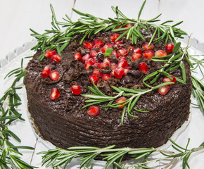 Chocolate cake decorated with pomegranate seeds and rosemary