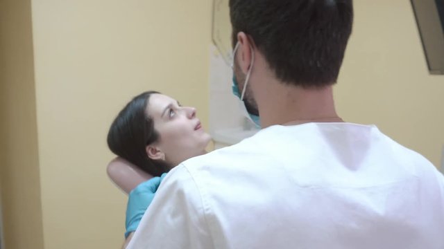 Beautiful young woman sitting in the dental chair in the clinic. the doctor examines the oral cavity. Steadycam shoot.