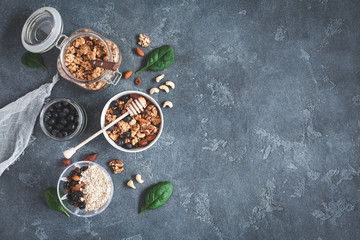 Obraz na płótnie Canvas Healthy breakfast with muesli, yogurt, blueberry, nuts on grunge background. Flat lay, top view
