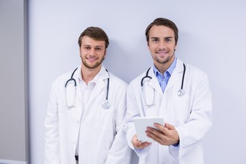 Portrait of doctors using digital tablet in corridor