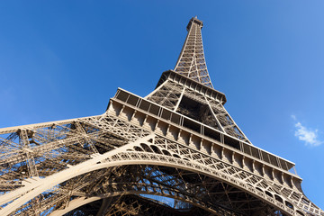 Fototapeta na wymiar Au pied de La Tour Eiffel ou de la Dame de Fer par une journée ensoleillée - Paris en France