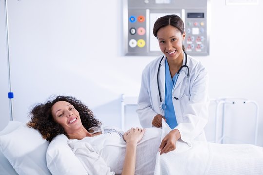 Portrait of doctor putting blanket on pregnant woman