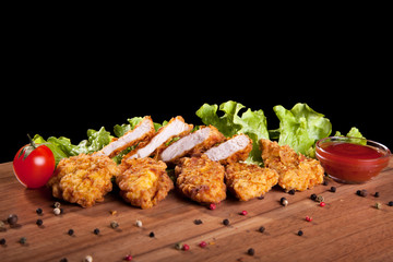 Chicken nuggets, on a wooden table with sauce and lettuce.
