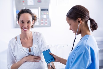 Doctor checking blood pressure of pregnant woman - obrazy, fototapety, plakaty