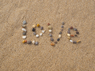 Fototapeta na wymiar word love written with stones and shells on the beach by the ocean