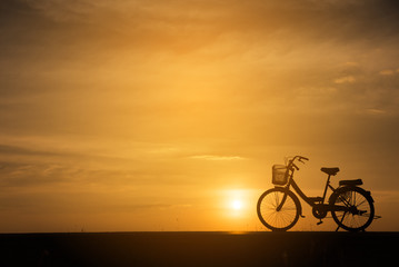 Silhouette of vintage bike .The background image is a sunset in Thailand.