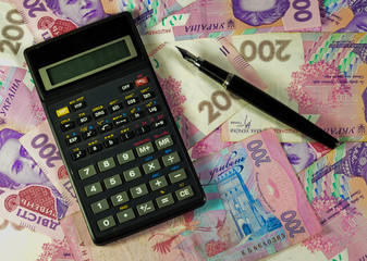 Calculator and fountain pen on background of the ukrainian money