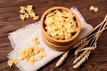 Raw pasta fettuccine in a wooden bowl