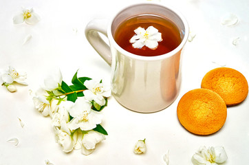 Tea cup with fragrant Jasmine flowers and biscuits on background