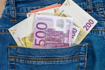 euro banknote into jeans pocket. close up.