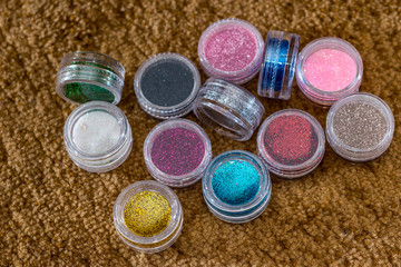 many round jars with  multi-colored bright glitter for nail polish.