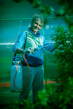 Woman is watering the trees in the garden