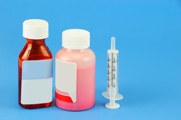 Prescription medicine bottle and oral syringe for baby isolated on blue background