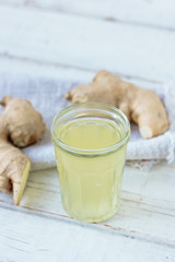 ginger juice in small glass jar with ginger root behind.