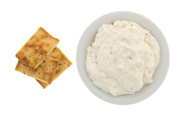 Seasoned rosemary and olive oil crackers with a bowl of French onion dip top view isolated on a white background.