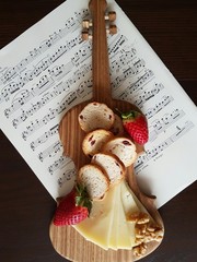 Fototapeta na wymiar Cheese and crusty bread on wooden board in the form of violin.