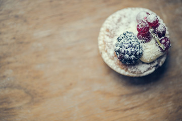 Pastry tarts with blackberries and red currants on a wooden board