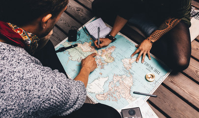 Couple making vacation plan sitting by the world map. - obrazy, fototapety, plakaty