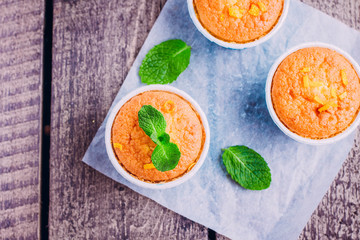 Fresh homemade orange muffin on wooden table background.