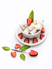 cup with marshmallow on plate with spoon, basil, strawberry