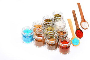 various spices in spoons and jars on white background