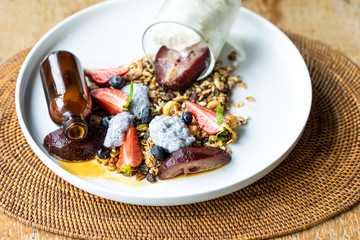 Yogurt with baked granola and berries in small bowl, strawberrie