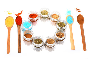 various spices in spoons and jars on white background
