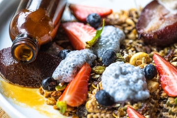 Yogurt with baked granola and berries in small bowl, strawberrie