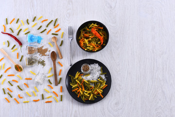 scattered pasta, plates, fork, spoons, chili pepper, spices