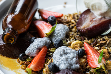 Yogurt with baked granola and berries in small bowl, strawberrie