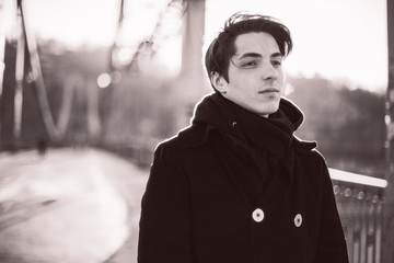 Thoughtful hipster guy walking on the bridge. Film sepia effect with grain