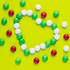 Candies in the shape of heart on yellow background