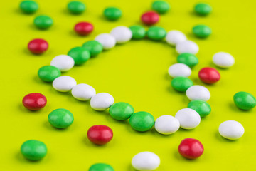 Candies in the shape of heart on yellow background