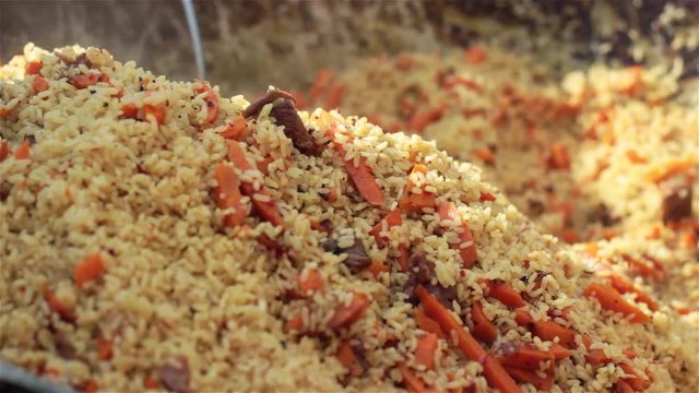 Pilaf (Plov) preparation Afghan, Uzbek Tajik national cuisine main dish large cast-iron cauldron on fire mixed ready pilaf sliced red carrot barberry garlic red chili pepper rice lamb mutton fat oil 