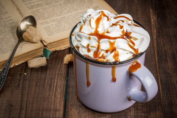 Concept of home relaxation: aromatic coffee or hot chocolate with whipped cream and caramel and old...