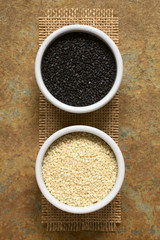 Black and white sesame seeds in small bowls, photographed overhead with natural light (Selective Focus, Focus on the seeds on the top)